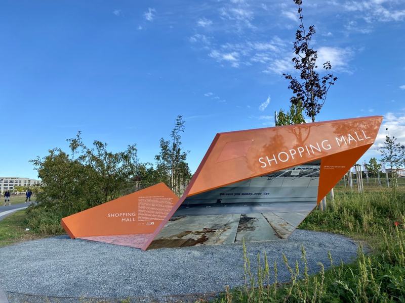 Eine der auffallenden, orangenen Stelen: Infotafel über die ehemalige Shoppingmall